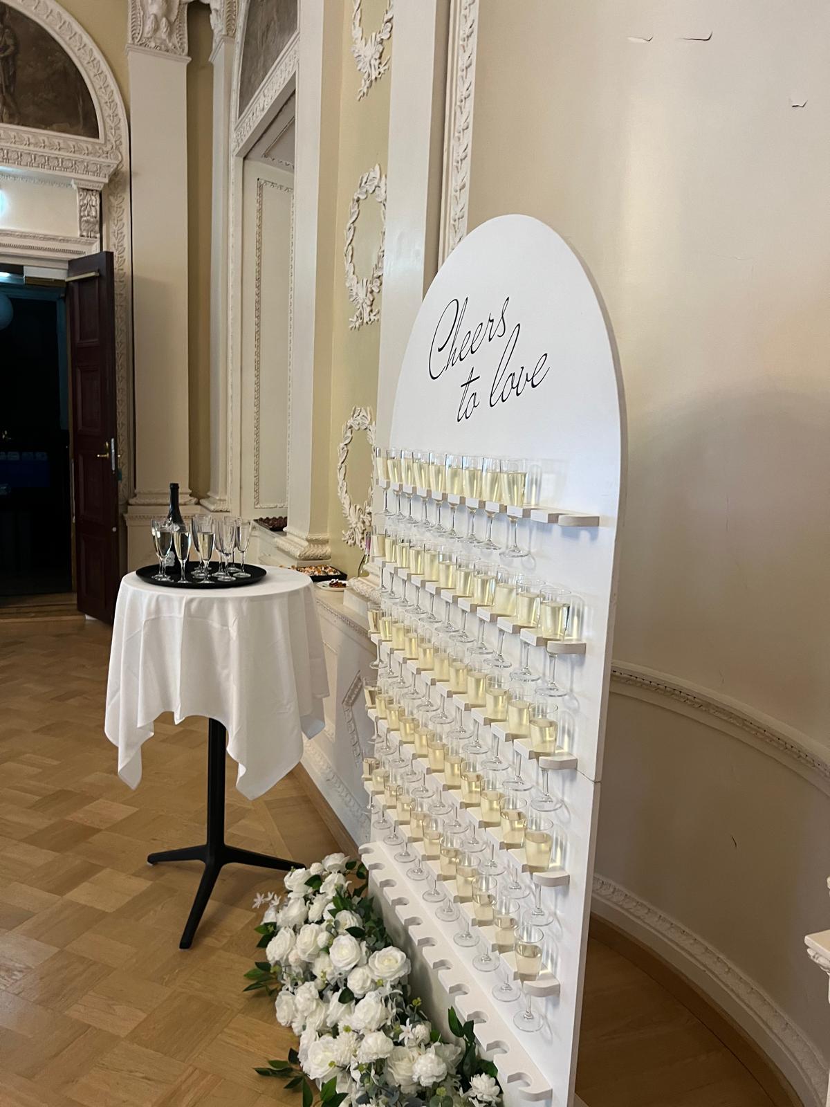 Hääkoristelu Helsinki – samppanjalasit ja Cheers to love -kyltti juhlatilassa